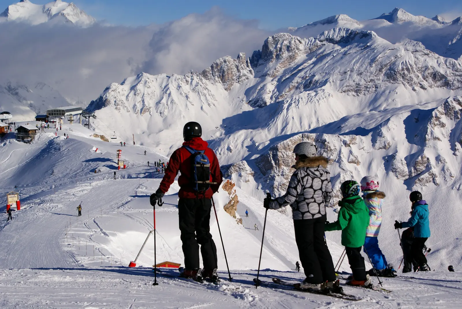 Familie mit Kindern auf der Piste vor verschneiten Bergen